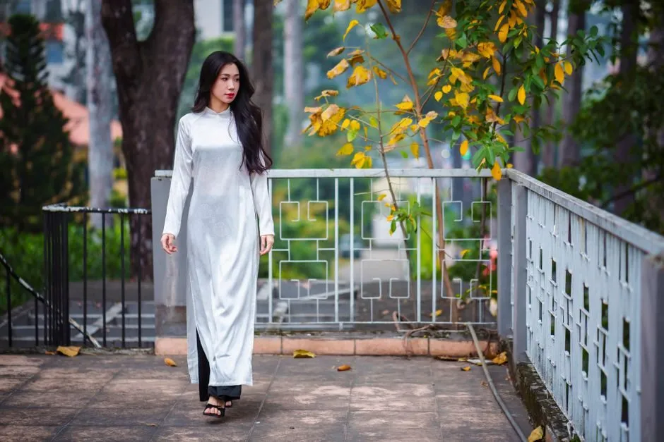 Người phụ nữ mặc áo dài đi dưới hàng cây ở Việt Nam